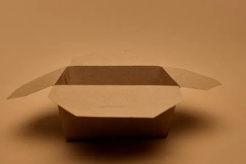 Open empty brown cardboard container on brown surface, eco packaging. Concept of Stock Photos
