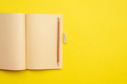 Open empty diary with a pencil and an  inscription idea on yellow background Stock Photos