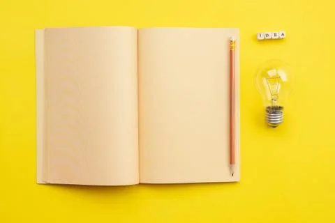 Open empty diary with a pencil and a bulb  and an  inscription idea on yellow Photos