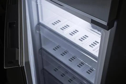 Open empty freezer drawer with bright cold light, clean shelves ready for foo Fotos de archivo