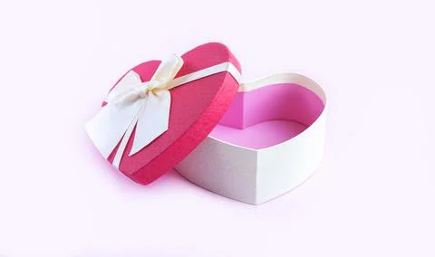 Open empty heart shape gift box with ribbon bow on pink table Foto stock