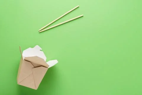 Open empty kraft paper box and chopsticks on green background. Stock Photos