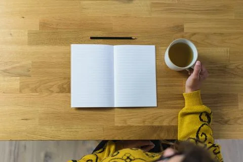 Open empty notebook and pencil, woman holding a mug with tea Stock Photos
