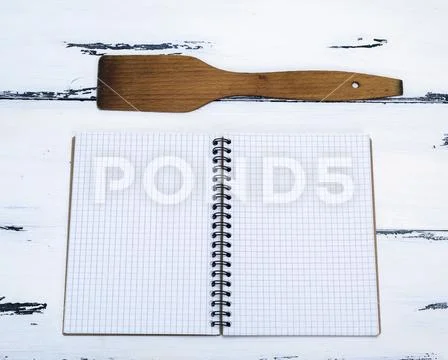 Open empty notebook in a box and a kitchen spatula Stock Photos