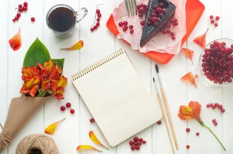 Open empty notebook with cup of coffee, cake and flowers Stock Photos