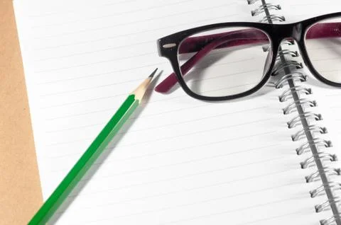 Open empty notebook with green pencil, eyeglasses and lined pages Stock Photos