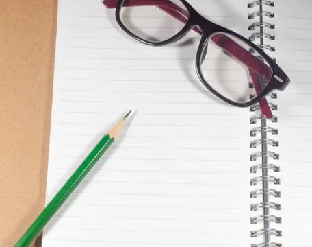 Open empty notebook with green pencil, eyeglasses and lined pages Stock Photos