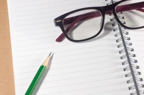 Open empty notebook with green pencil, eyeglasses and lined pages Stock Photos