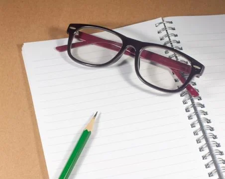 Open empty notebook with green pencil, eyeglasses and lined pages Stock Photos