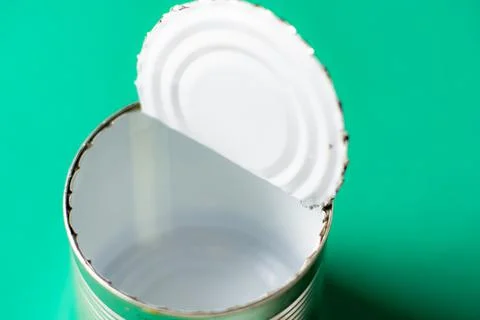Open empty tin can on a green background. Stock Photos