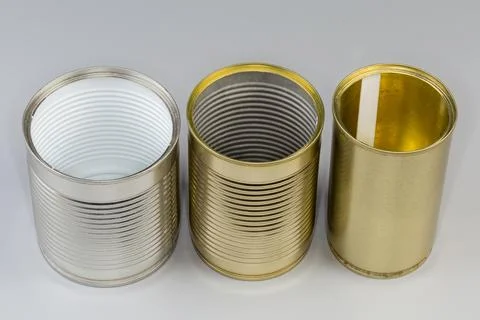 Open empty white and yellow tin cans on gray background Stock Photos