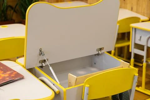 Open empty yellow school desk with storage compartment in a primary school .. Stock Photos