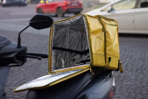 Open empty yellow thermo bag for delivery food and drink on black moped Stock Photos