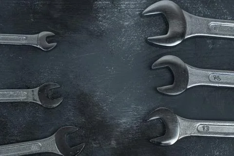 Open-end wrenches facing inward on dark textured background. Stock Photos