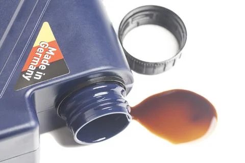 Open engine oil bottle with a puddle of engine oil isolated on white backgr.. Stock Photos