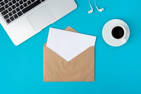 Open envelope with blank paper sheet on turquoise background. Keyboard, cup of Foto stock