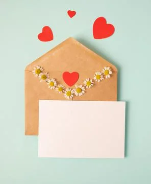 Open envelope with blank sheet of paper and red cute paper hearts, chamomile Фото
