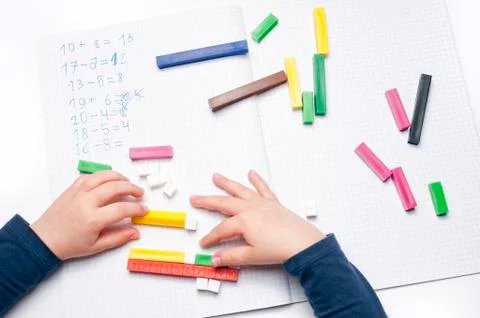 Open exercise book with colored plastic number rods on white background. Stock Photos