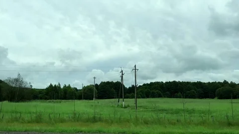 Open field and forest seen from a car's side window. Overcast sky covers th.. Stock Footage 340545437