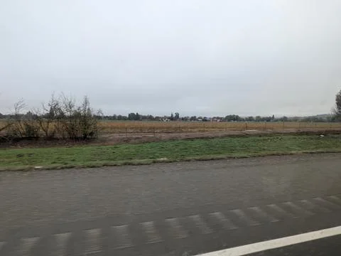 Open field near freeway with distant buildings under grey Stock Photos