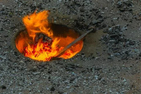 Open fire pit with glowing coals, flames and metal rod heating in rustic ou.. Stock Photos