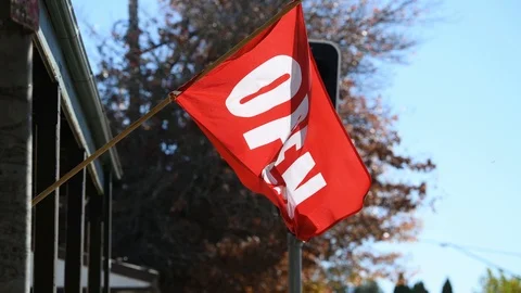 Open flag waving in the wind outside a store near a set of traffic lights Stock Footage 107349739