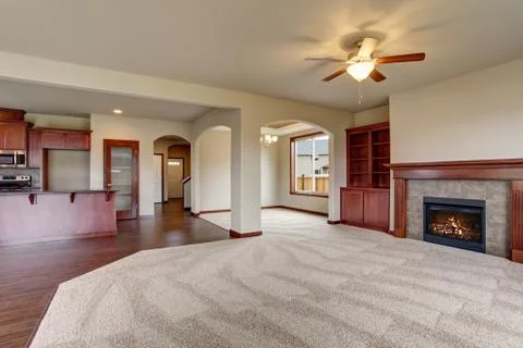 Open floor plan interior with carpet floor and fireplace connected with kitch Stock Photos