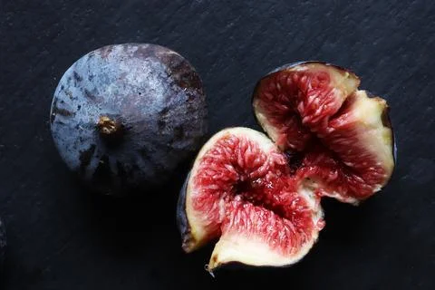 An open fresh red fig and a closed one on slate background for food illusta.. Stock Photos