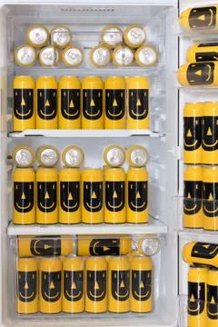 The open fridge is full of colored cans with a drink. Stock Photos