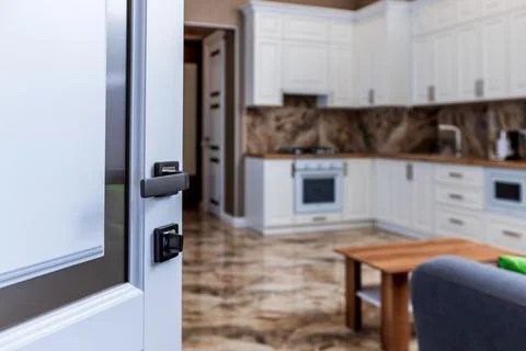 The open front door to the kitchen. White kitchen with wooden countertop and  Stock Photos