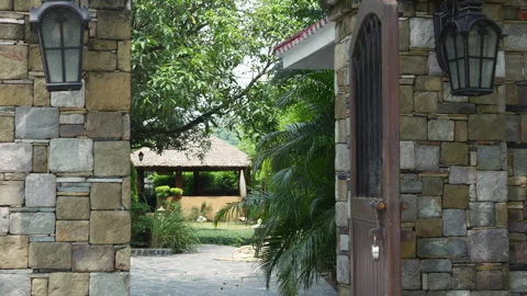 Open gates invite to a lush Indian jungle resort, stone pillars standing guard Stock Footage 270528990