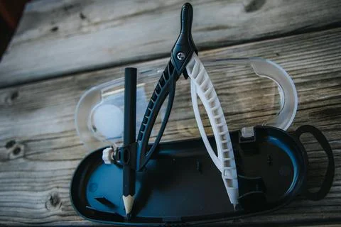 Open geometry compass set with a short black pencil stored. Stock Photos