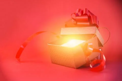 Open Gift Box rays light on red background red present box with red ribbon bo Stock Photos