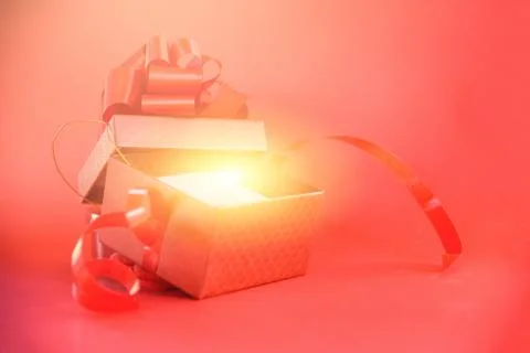 Open Gift Box rays light on red background / red present box with red ribbon  Stock Photos