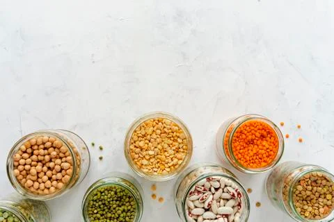 Open glass jars full of assorted dried legumes Foto stock
