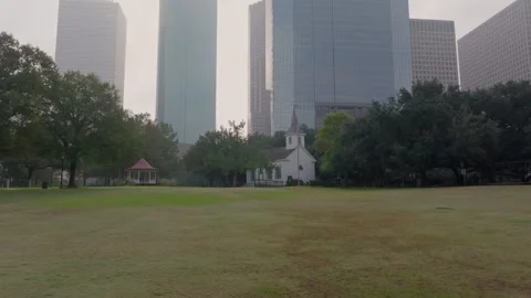 Open grass area in Sam Houston Park with a reveal of Houston skyline Stock Footage 278571305