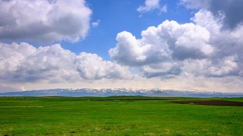Open grassland meets mountain range under dramatic cloud cover Foto stock