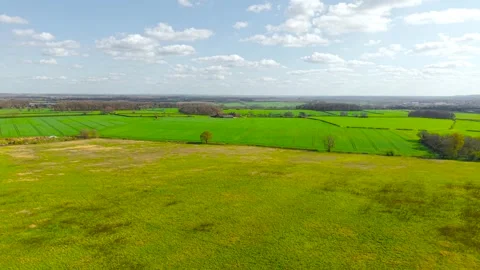 Open grassy field in foreground transitioning into structured agricultural plots Stock Footage 336542502