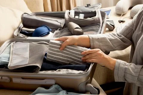 Open grey suitcase with different clothes packed for journey at home. Nordic Stock Photos