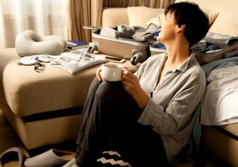 Open grey suitcase with different clothes packed for journey at home. Nordic Stock-Fotos