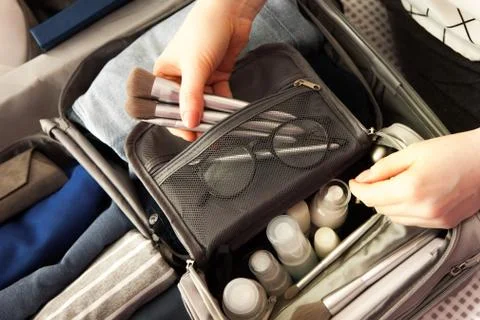 Open grey suitcase with different clothes packed for journey at home. Nordic Stock Photos