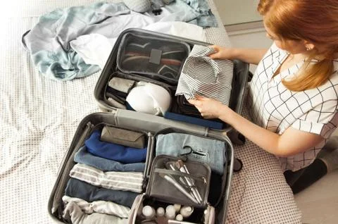 Open grey suitcase with different clothes packed for journey at home. Nordic Stock Photos