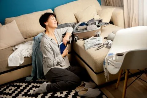 Open grey suitcase with different clothes packed for journey at home. Nordic Stock Photos