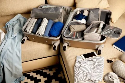 Open grey suitcase with different clothes packed for journey at home. Nordic Stock Photos