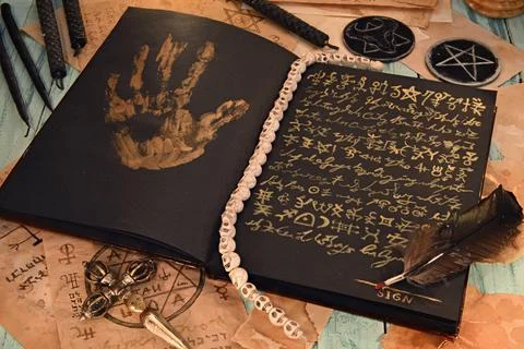 Open grimoire book of magic spells with black candles on witch table, sell so Photos