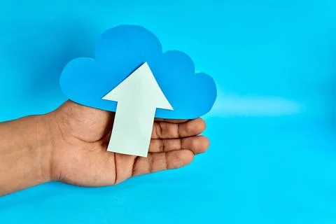 Open hand presenting blue cloud with white upload arrow on blue background 写真素材