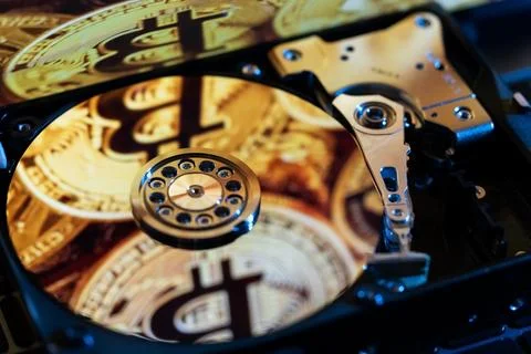 An open hard drive with reflections of gold Bitcoin coins on its surface Stock Photos