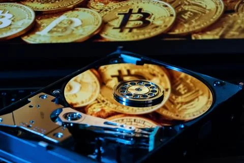 An open hard drive with reflections of gold Bitcoin coins on its surface Stock Photos