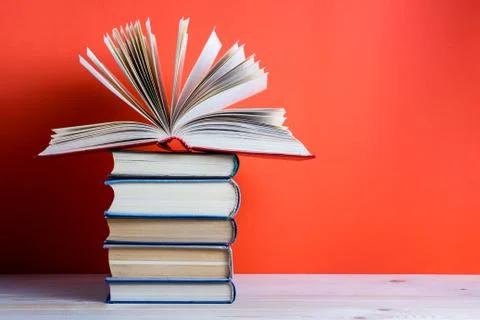 Open hardback book on wooden deck table and red background Stock Photos