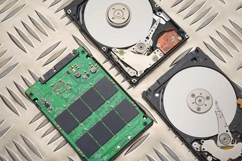 Open HDD and SSD disk drives on metal plate background Stock Photos